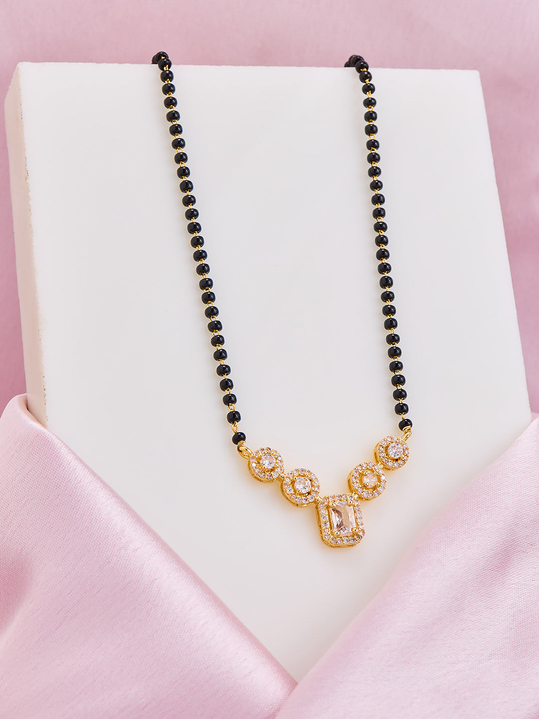 Necklace with black beads and gold clasp on a pink satin surface