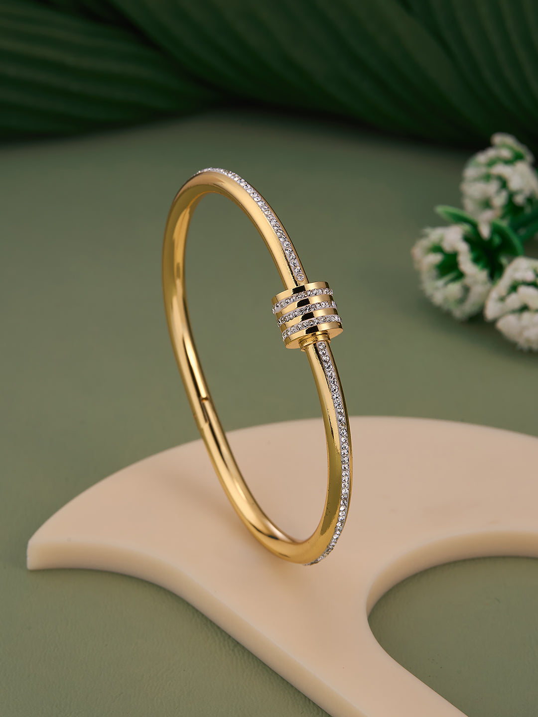 Gold bracelet with diamond accents on a green background