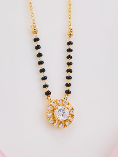 Necklace with black beads and a gold pendant on a light gray background