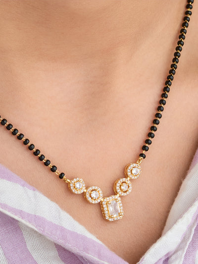 Necklace with black beads and gold and crystal pendant on a person wearing a light purple saree.