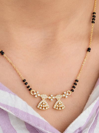 Gold necklace with black beads on a person wearing a light purple garment.