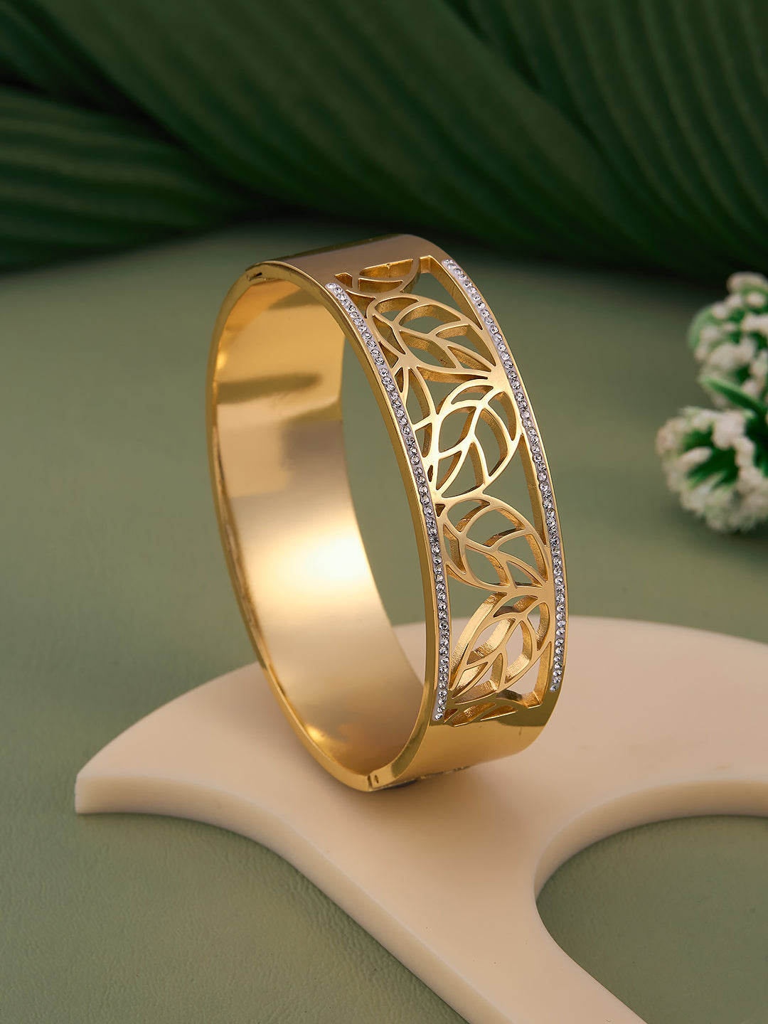 Gold bracelet with intricate design on a green surface