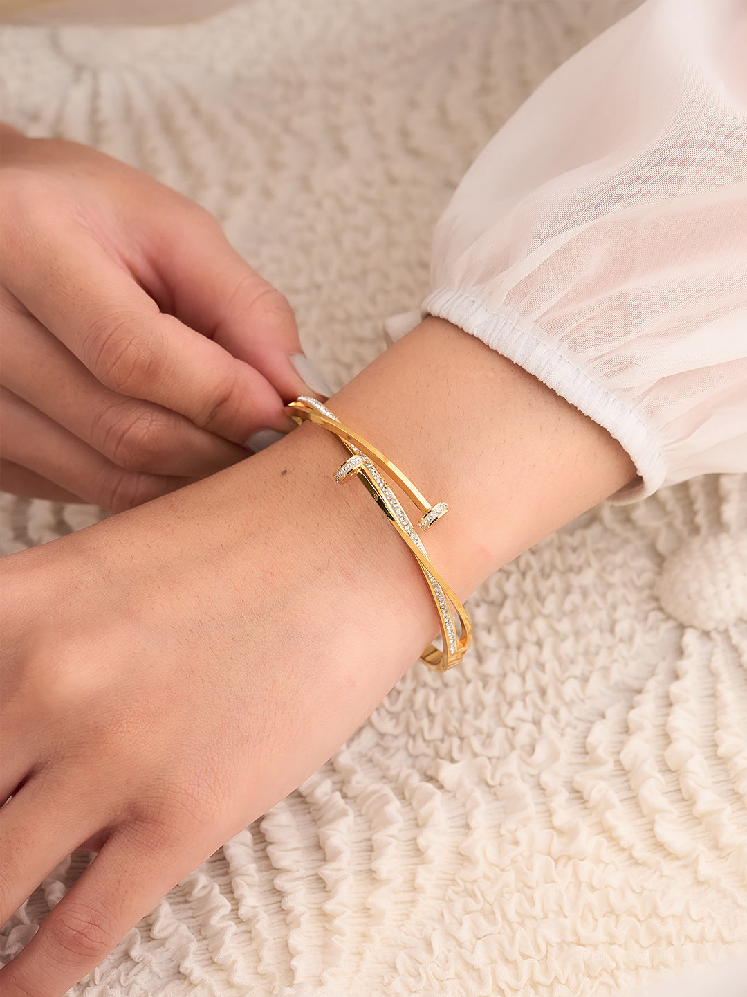 Gold bracelet being worn on a wrist with a soft background