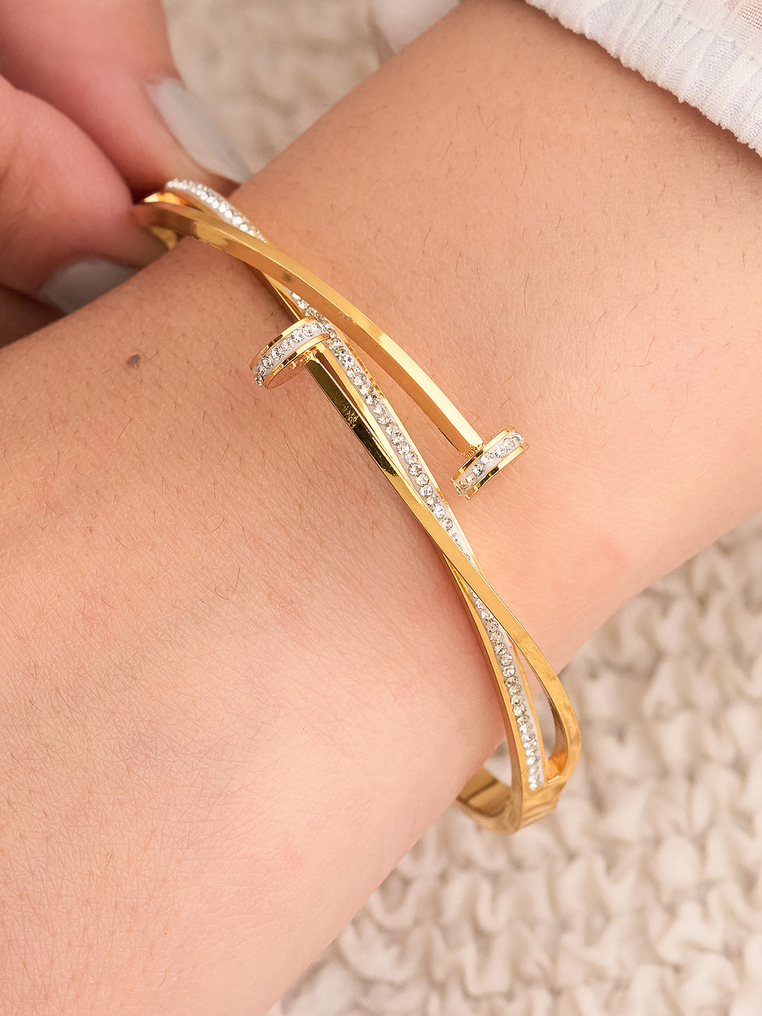 Gold bracelet with diamond accents on a wrist against a neutral background