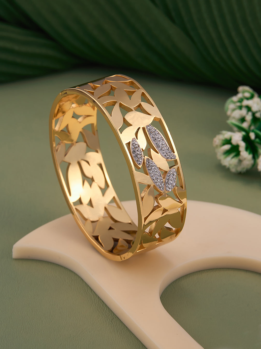 Gold bracelet with leaf designs on a green background