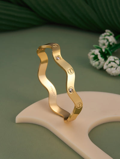 Gold bracelet with wavy design on a green background