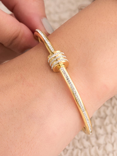 Gold bracelet with diamond accents on a wrist against a neutral background