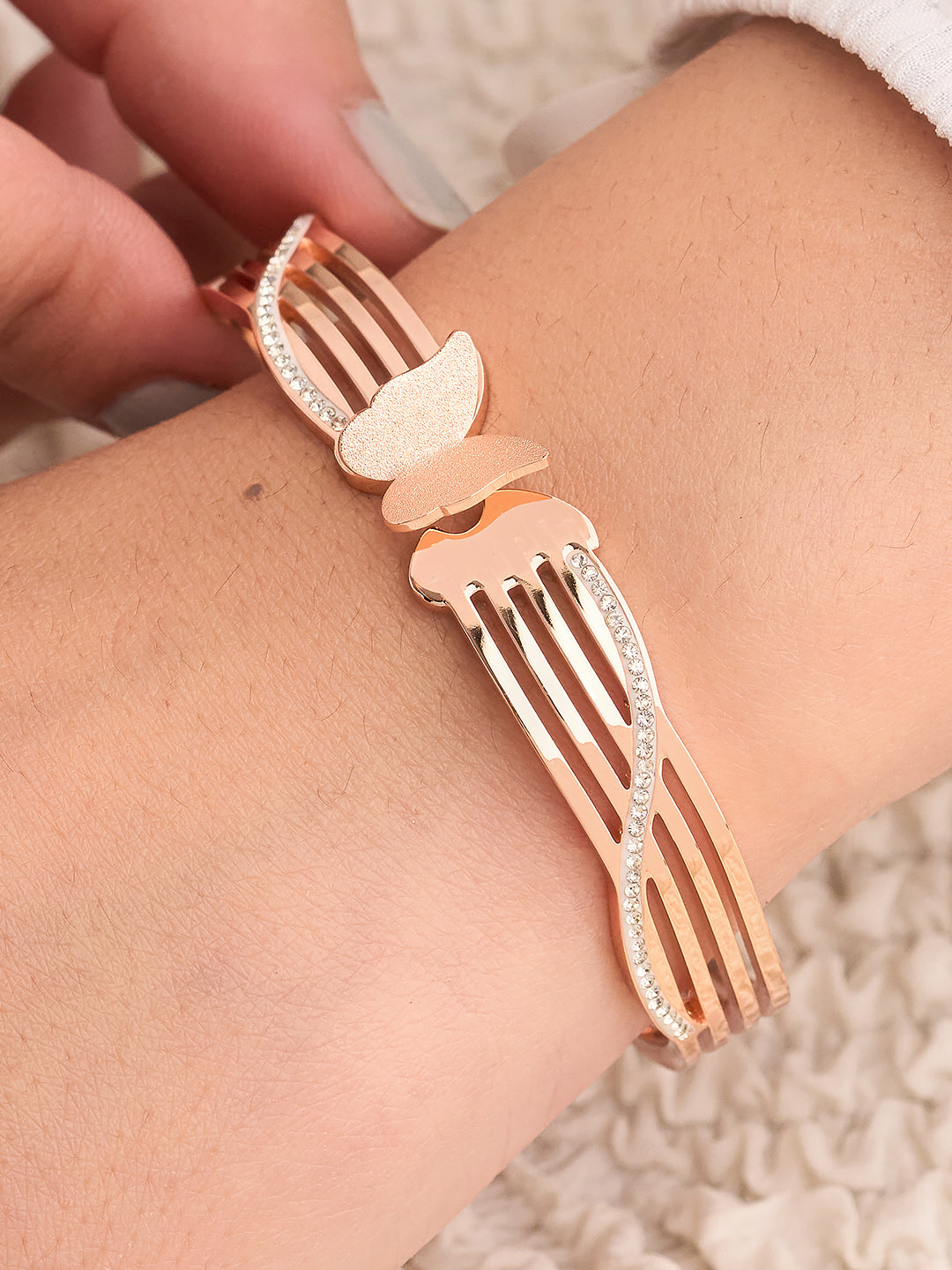 Rose gold fork-shaped bracelet on a wrist with a blurred background